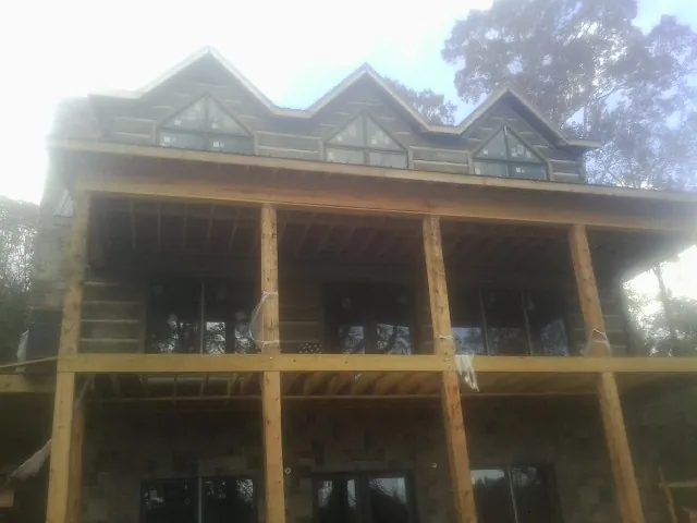 Dormers and porch framing on a large log home under construction — Roof Coating work by our crew in Dushore