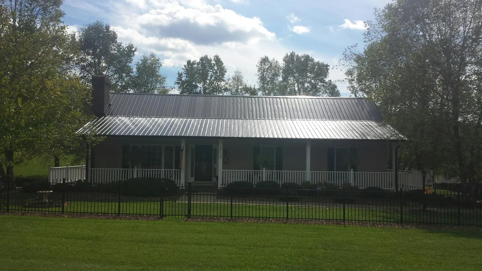 Gray metal roof on a brick ranch with a full width front porch — Gutter Guard Installation work by our crew in Dushore