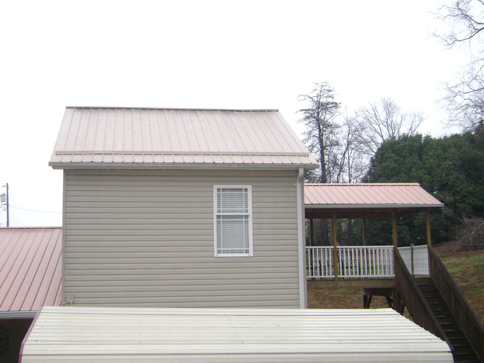 Tan metal roofs on a two story addition and attached porch, from a Roof Replacement job in Dushore