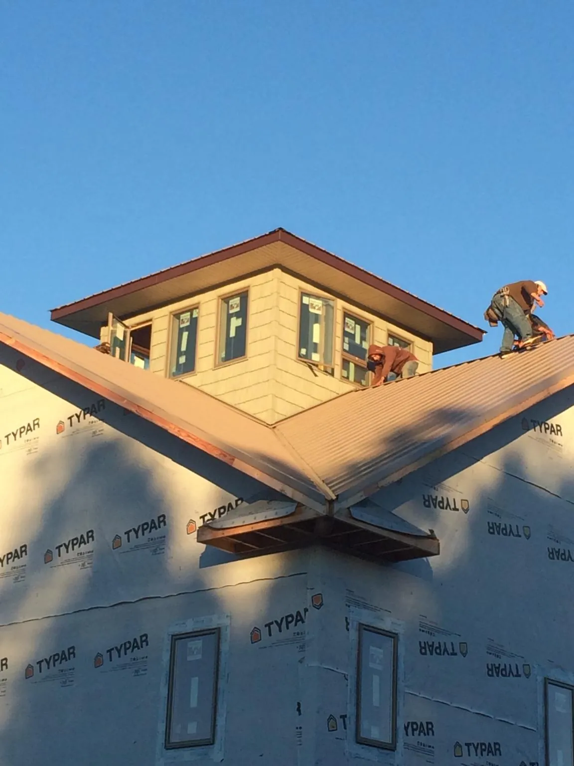 Roofers working around a rooftop cupola on a new metal roof at sunset — Roof Waterproofing in Dushore by Roofing Brothers
